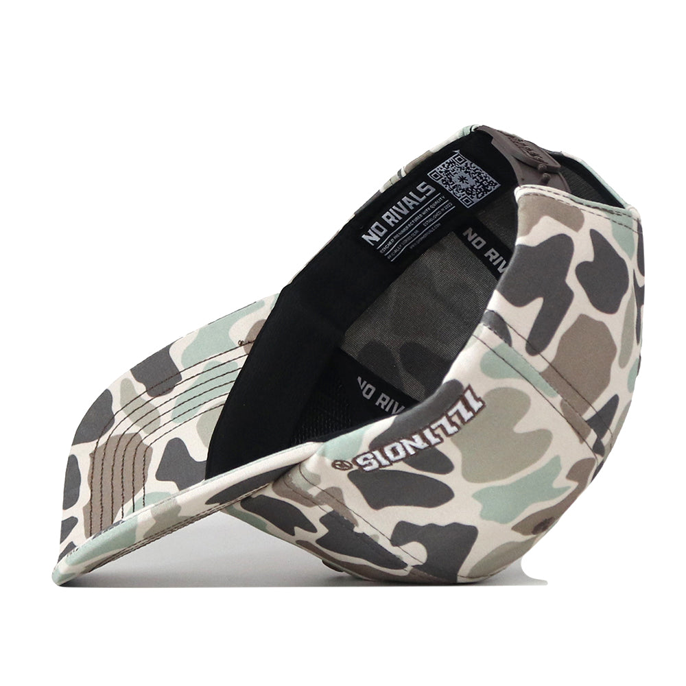 The Illinois Huntsman Hat by No Rivals is displayed tilted on its side to reveal the inside, which features black lining and bold NO RIVALS text. The camo-patterned outer brim showcases ILLZIONS embroidered in crisp white letters, making it an ideal choice for gameday. This snapback style includes an eye-catching embroidered logo that ensures you stand out in any crowd.