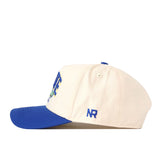 A cream South Dakota State Jackrabbits Stadium Hat by No Rivals, featuring a blue brim and side view. The embroidered blue NR logo sits above the brim, adding a subtle branded detail perfect for your gameday look.
