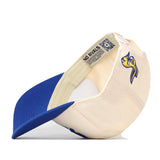 A cream and blue snapback hat, the South Dakota State Jackrabbits Stadium Hat by No Rivals, is shown flipped upside down to display a QR code label and the “NO RIVALS” text inside. The cap features an officially licensed embroidered Jackrabbit logo on the side.
