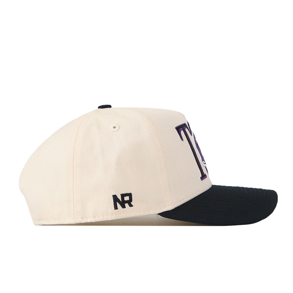 Introducing the TCU Aer Lingus Football Hat by No Rivals—a cream-colored cotton baseball cap featuring a black brim, bold purple embroidered lettering on the front, and the NR initials stitched in black on the side. Designed for both durability and style, this high-quality hat offers a comfortable fit with its convenient snap-back adjustment.