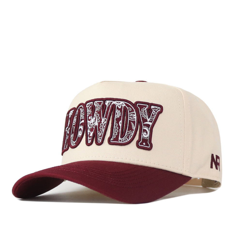 Introducing the Texas A&M Paisley Howdy Hat by No Rivals: This officially licensed snapback features a cream and maroon design, highlighted by large “HOWDY” letters in a paisley pattern across the front. The maroon brim and an embroidered logo add a premium, authentic touch to this stylish cap.