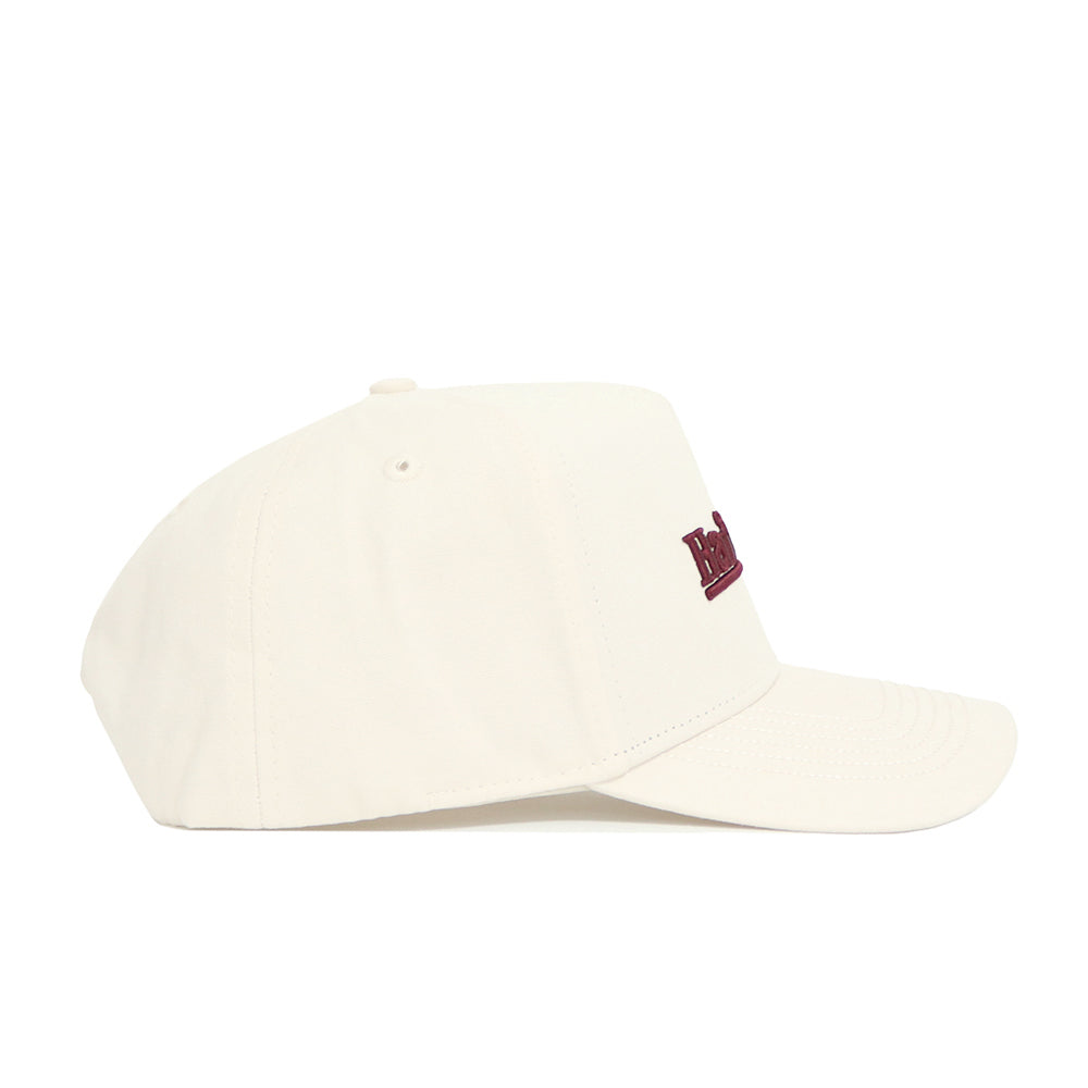 The No Rivals Mississippi State Sideline Hat, made of premium cotton in plain ivory, is shown from the side with stitched eyelets and a partially visible red embroidered logo on the front.