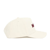 The No Rivals Mississippi State Sideline Hat, made of premium cotton in plain ivory, is shown from the side with stitched eyelets and a partially visible red embroidered logo on the front.