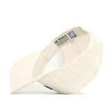 The Michigan State Sideline Hat by No Rivals is pictured upside down, showing its cream color, structured fit, interior label with "NO RIVALS" and QR code, plus the underside of the brim and cap's interior.