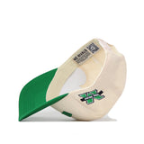 An Upside Down The Herd Hat by No Rivals is flipped upside down, revealing the inside label “NO RIVALS” and a QR code. The cream and green snapback baseball cap features a large green “N” with "THE GRID" embroidered below it on the exterior.