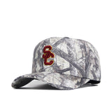 The USC Outland Hat by No Rivals is a gray camo snapback with a red and gold SC logo embroidered on the front, made from premium cotton for a structured, comfortable fit.