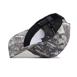 The South Dakota State Outland Hat by No Rivals is displayed upside down, showing its camouflage pattern, structured fit, inner lining, sweatband with "NO RIVALS" text, and a white paper insert beneath the crown.
