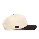 The No Rivals Penn State Espresso Hat is a cream-colored baseball cap with a brown brim, shown from the side. Crafted from high-quality cotton, this structured fit hat features a small brown silhouette of Pennsylvania near the back and includes an adjustable snapback closure for comfort.