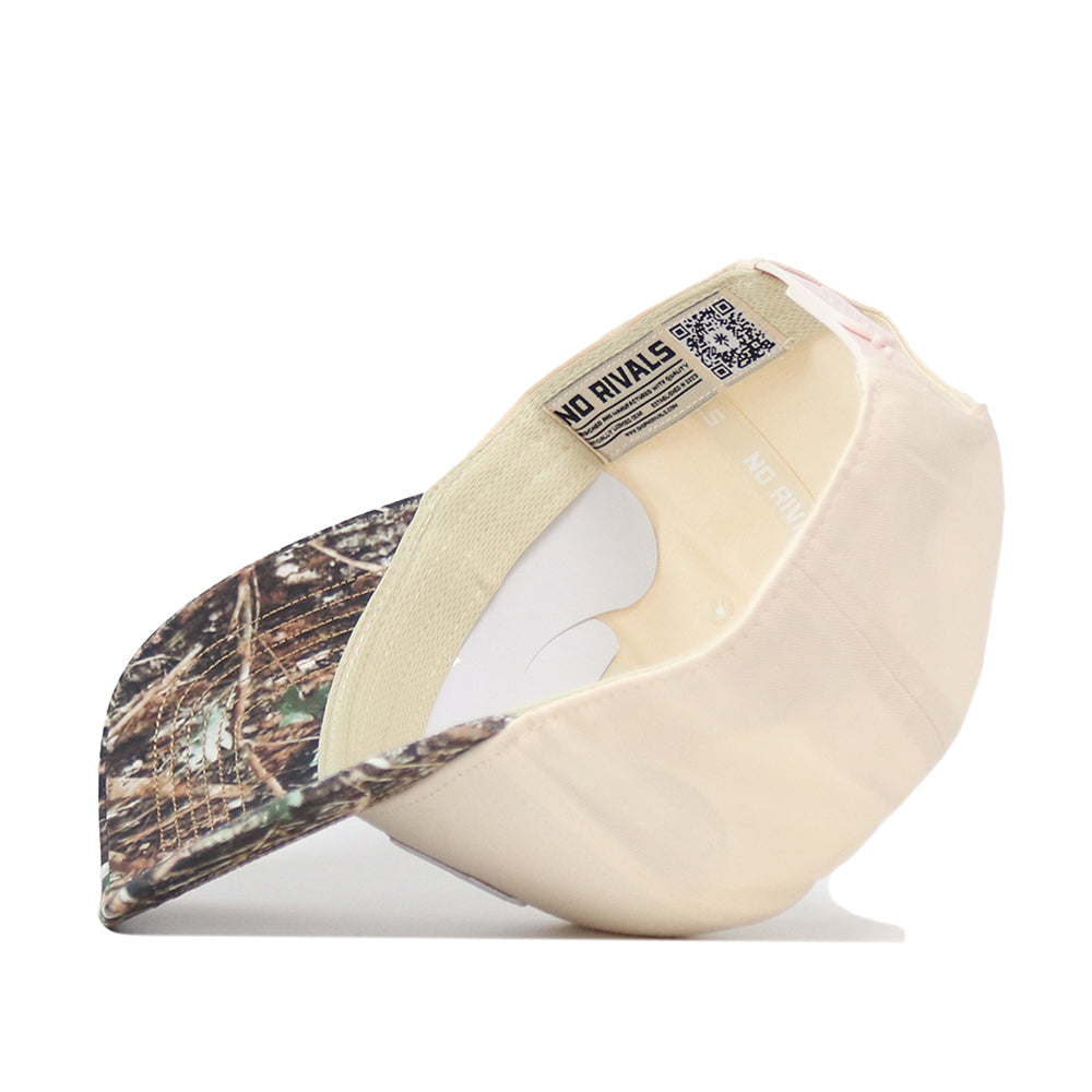 The Wisconsin Camo Connector Hat by No Rivals is shown upside down, revealing the inside labels and stitching. This snapback cap features a curved brim with a woodland pattern, embroidered logos on the front, and a No Rivals tag near the inner band—ideal for elevating your gameday fit.