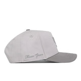 A light gray UNT Graphite Hat by No Rivals is shown from the side, featuring “Mean Green” embroidered in cursive near the back. The hat includes a curved bill, visible stitching, and a convenient Snap Back Adjustment for a customized fit.