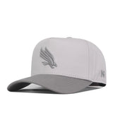 The No Rivals UNT Graphite Hat is a light gray baseball cap featuring an officially licensed embroidered bird logo on the front and a curved brim. It also has small stitched details, including letters, on the side of the cap.