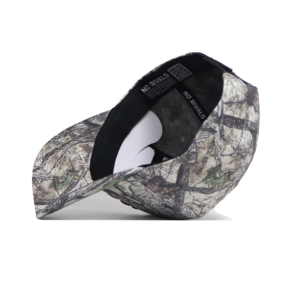 The Montana Outland Hat by No Rivals is a premium cotton camouflage baseball cap with "NO RIVALS" printed on the inner band. Shown upside down to highlight its structured fit and brim against a white background.
