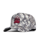 The Montana Outland Hat by No Rivals is a camouflage snapback featuring a red bear paw print logo on the front, made from high quality cotton and displayed against a white background.