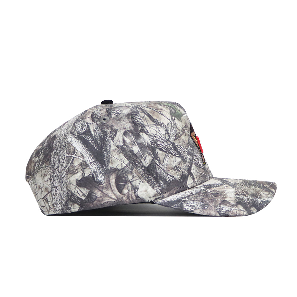 The No Rivals Maryland Outland Hat is a camouflage snapback with a flat brim, shown in side profile. Made from high quality cotton, it features earth tones and leaf patterns in classic camo style.