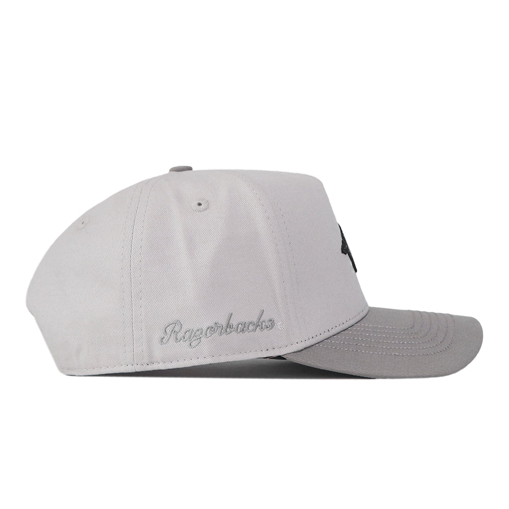A light gray Arkansas Graphite Hat by No Rivals is shown from the side, featuring “Razorbacks” embroidered in cursive above the brim for a standout logo and classic gameday fit.