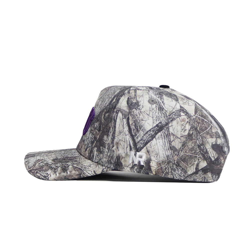 Side view of the No Rivals TCU Outland Hat, a structured-fit baseball cap in brown, gray, and beige woodland camo. Features a large white "M" and small "NR" embroidery on the side plus snap back adjustment. Officially licensed.