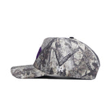Side view of the No Rivals TCU Outland Hat, a structured-fit baseball cap in brown, gray, and beige woodland camo. Features a large white "M" and small "NR" embroidery on the side plus snap back adjustment. Officially licensed.