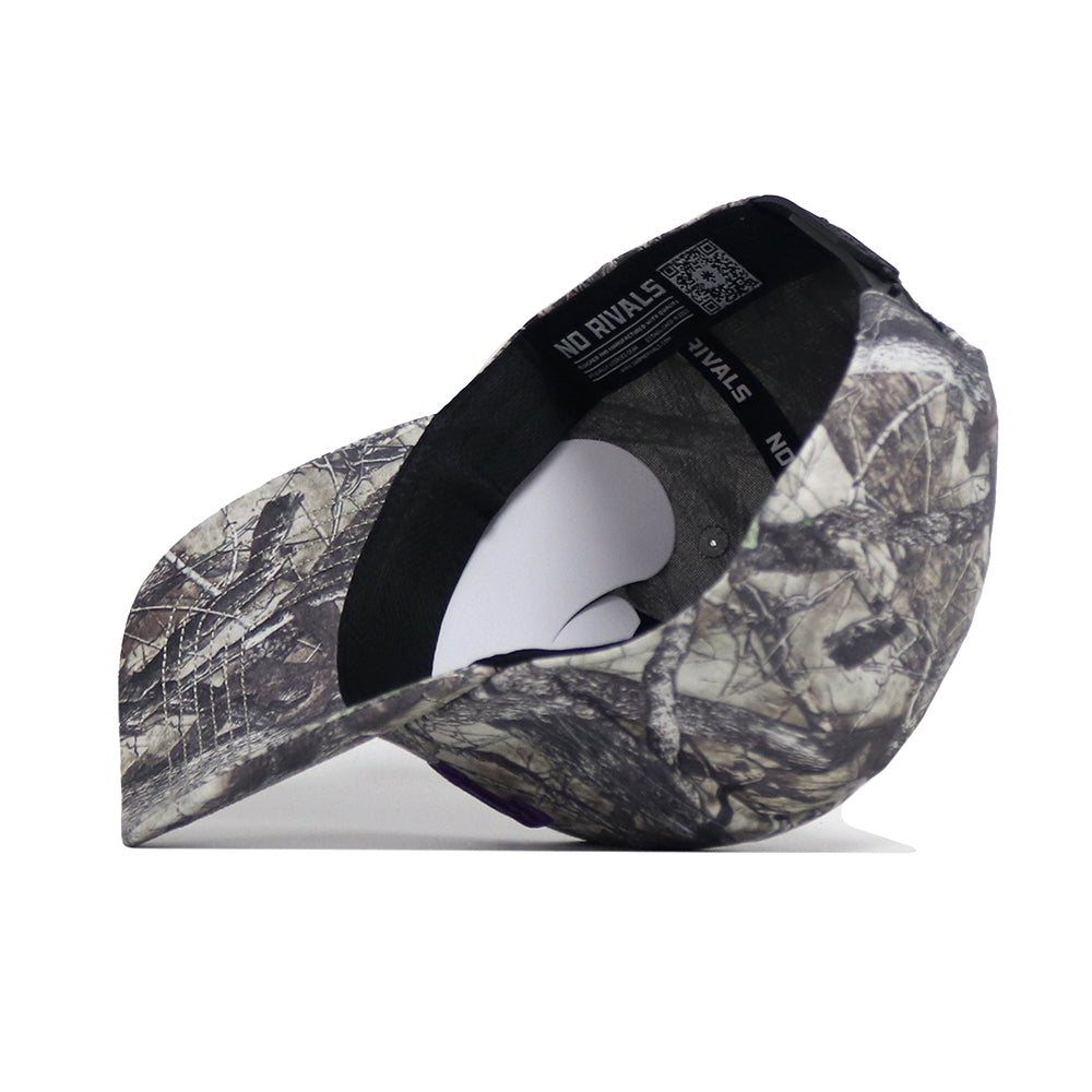 The TCU Outland Hat by No Rivals is shown upside down, revealing its camo interior, black sweatband, and white NO RIVALS label. Bill points left. Offers a structured fit and snapback adjustment for comfort.