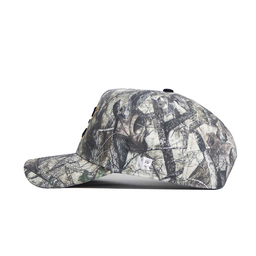 The No Rivals ETSU Outland Camo Hat features a side view of its camouflage pattern, a curved brim, embroidered white NB logo near the back, and a structured fit for added style.