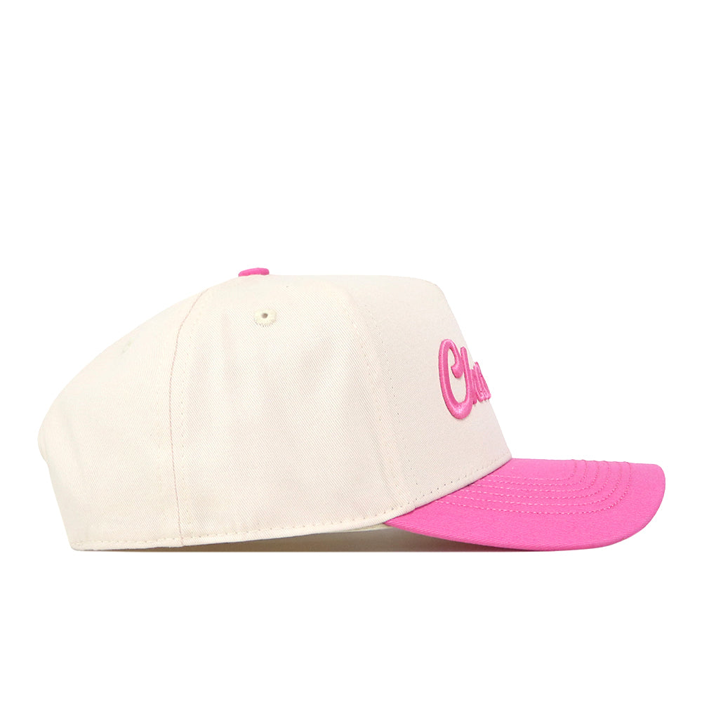The UNC Charlotte Pink Out Hat by No Rivals is a cream-colored baseball cap crafted from high-quality cotton, featuring a bright pink brim and pink embroidered lettering on the front, displayed in a side profile view against a white background.