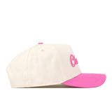 The UNC Charlotte Pink Out Hat by No Rivals is a cream-colored baseball cap crafted from high-quality cotton, featuring a bright pink brim and pink embroidered lettering on the front, displayed in a side profile view against a white background.