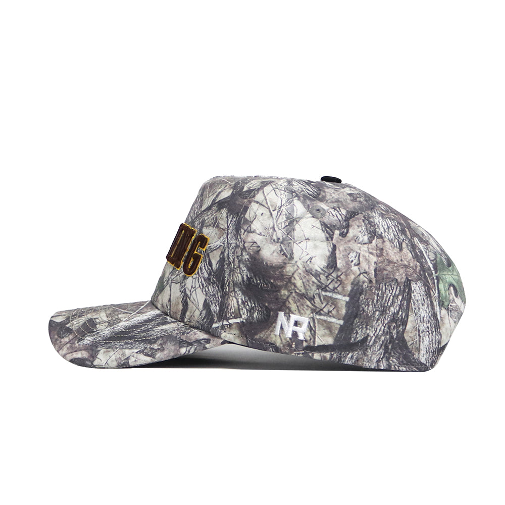 The No Rivals Wyoming Outland Hat is a camo snapback with a structured fit and flat brim, featuring white "NH" on the side and yellow text partially visible on the front, shown in side profile.