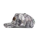 The No Rivals Wyoming Outland Hat is a camo snapback with a structured fit and flat brim, featuring white "NH" on the side and yellow text partially visible on the front, shown in side profile.