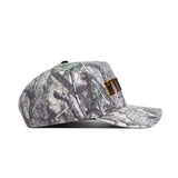 The No Rivals Wyoming Outland Hat is a camouflage snapback made from high-quality cotton, featuring brown embroidered letters on the front and displayed in a side profile view against a white background.