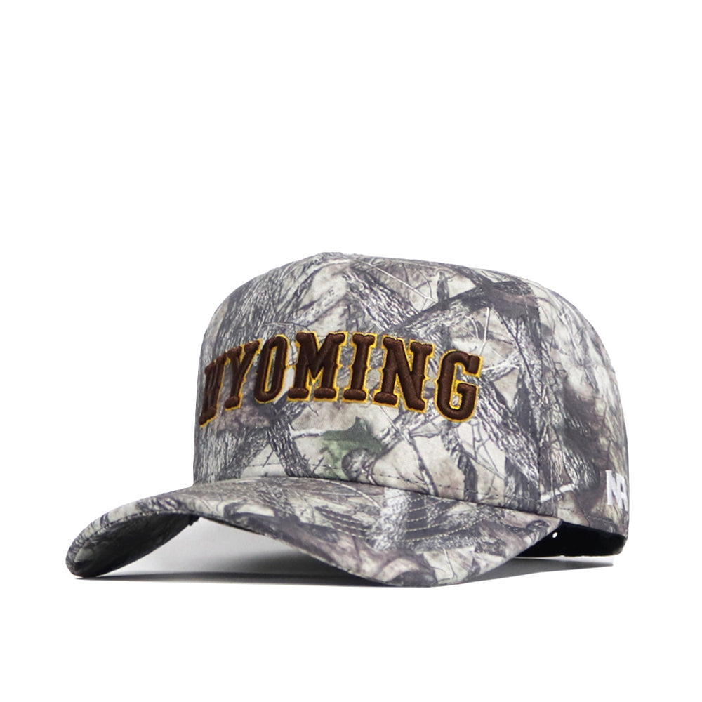 The No Rivals Wyoming Outland Hat is a structured cotton baseball cap with "WYOMING" boldly embroidered in yellow on the front. It features a curved brim and camouflage fabric in gray, brown, and green shades.