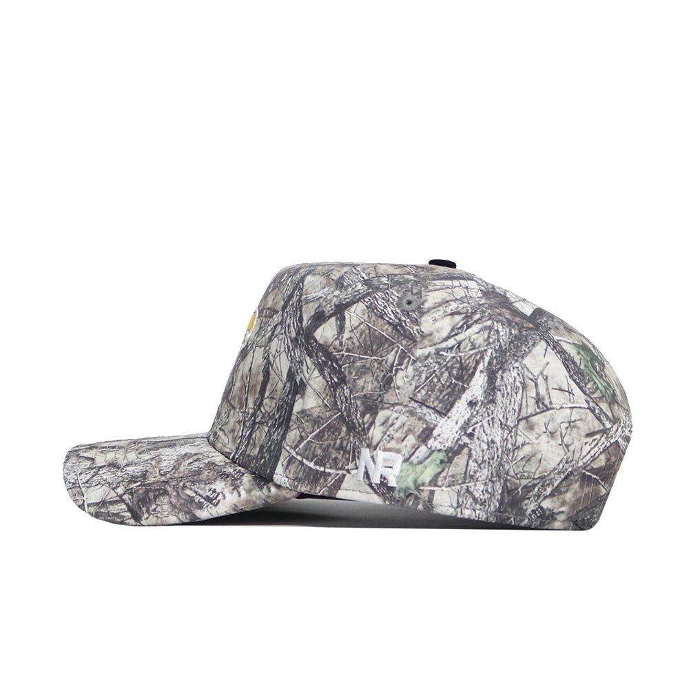 Side view of the No Rivals Kansas Outland Hat, a flat-brim snapback with realistic forest camo and a small white NE logo near the back, crafted from high-quality cotton for a structured fit.