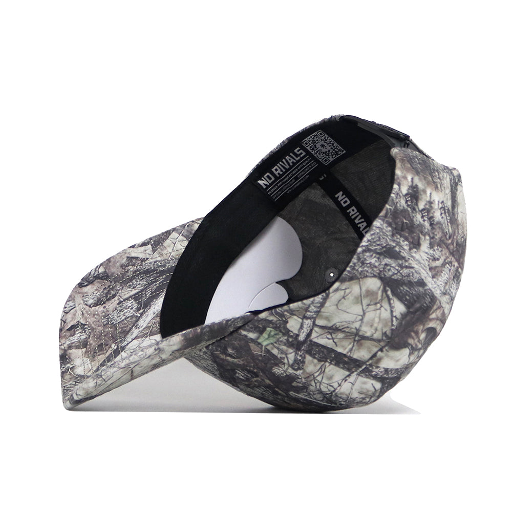The Kansas Outland Hat by No Rivals is a structured-fit camouflage baseball cap made of high-quality cotton, featuring a curved brim, inner black band, and white NO RIVALS tag. Its woodland-inspired pattern stands out with premium craftsmanship.