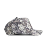 A side view of the No Rivals Colorado State Outland Hat, a snapback with a camouflage design of tree branches and leaves in muted brown, gray, and green cotton for a comfortable, structured fit.