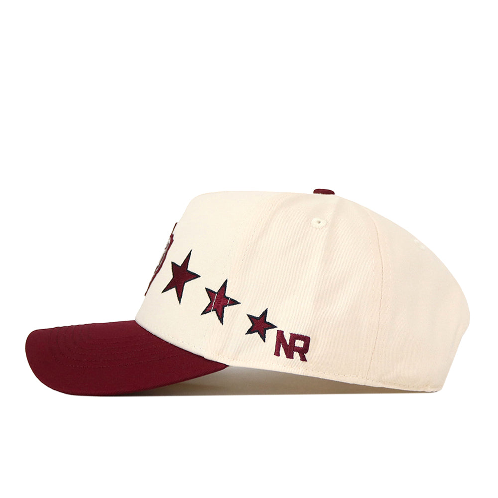 Introducing the Texas A&M Star Hat by No Rivals—a cream-colored baseball cap with a maroon bill, adorned with four maroon stars and “NR” embroidered on the side. This officially licensed snapback cap also features a finely embroidered Texas A&M logo for an added touch of style.