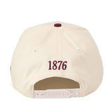 A white snap back Texas A&M Star Hat by No Rivals is shown from the back, featuring “1876” embroidered in maroon above the adjustable strap, along with an officially licensed embroidered logo.
