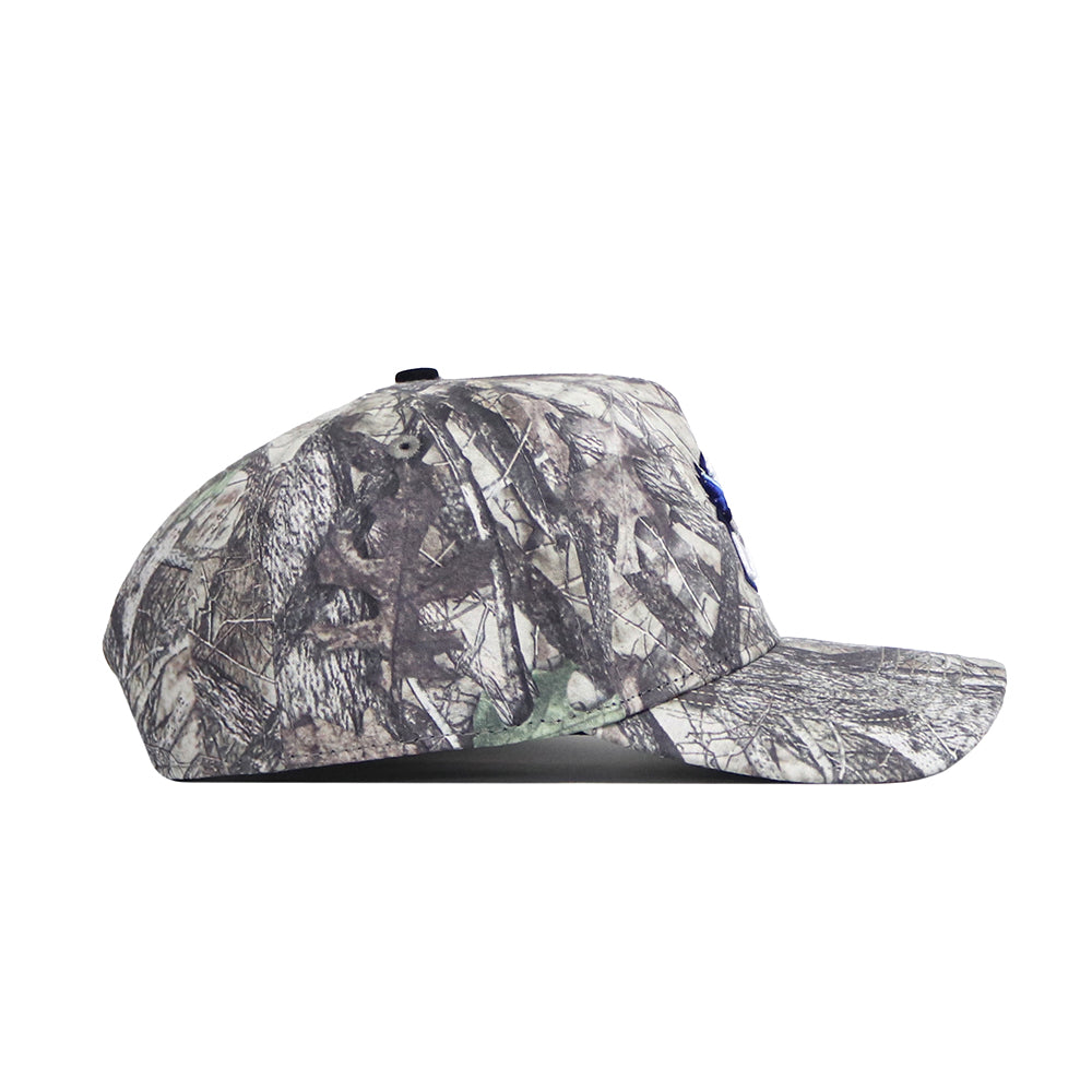 Side view of the Creighton Outland Hat by No Rivals, a structured fit cap with a gray and brown camo pattern, flat brim, classic top button, and high-quality cotton material.