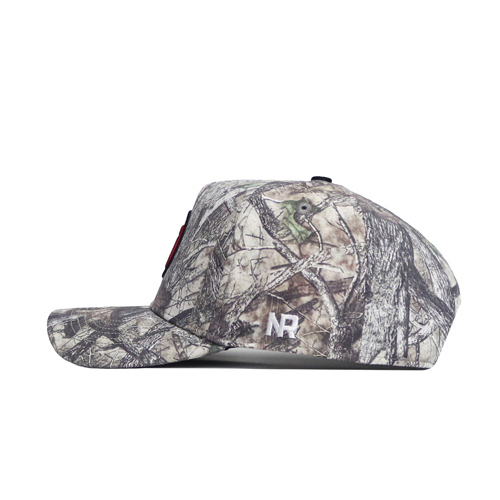 Side view of the Utah Outland Hat by No Rivals, a high-quality cotton snapback with woodland camo on the bill, crown, and button. White embroidered NR initials are featured near the back.