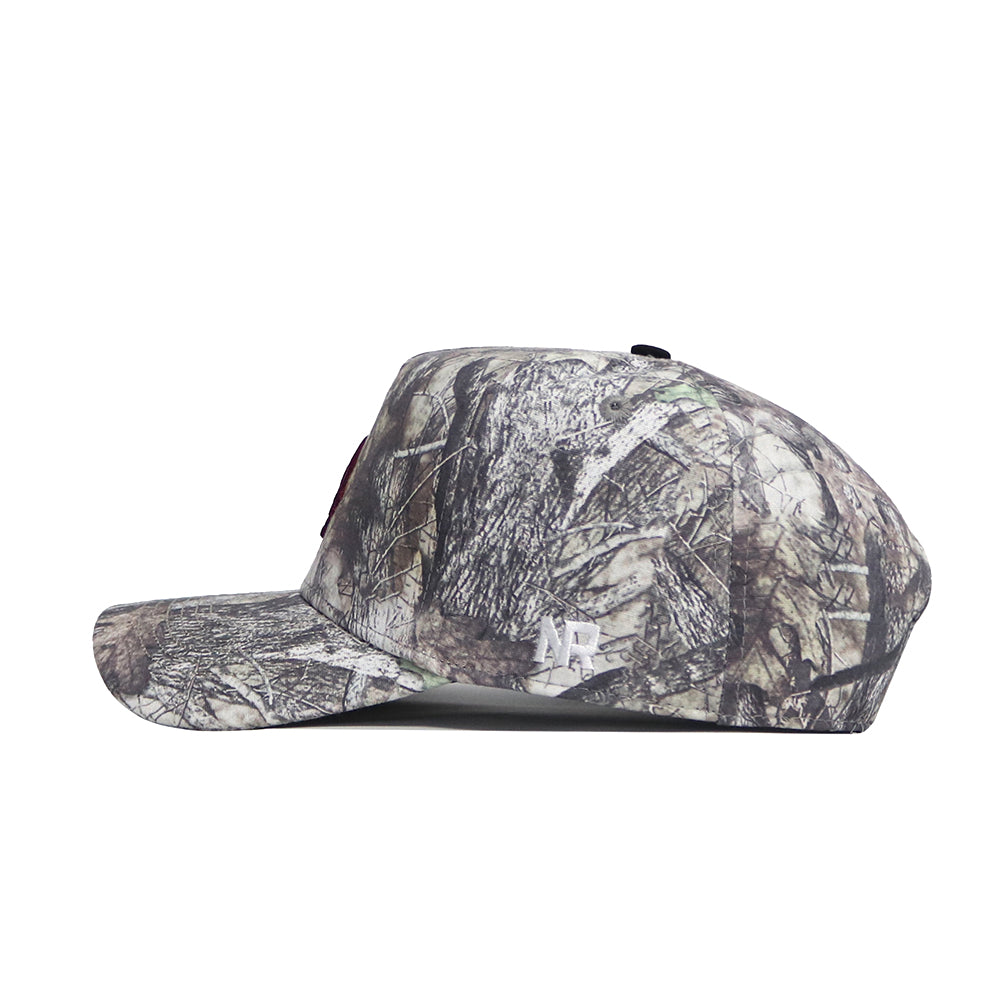 The No Rivals Texas State Outland Hat is a side-view camouflage baseball cap in brown, green, and gray cotton, featuring a structured fit, curved brim, and a small white embroidered logo near the back.