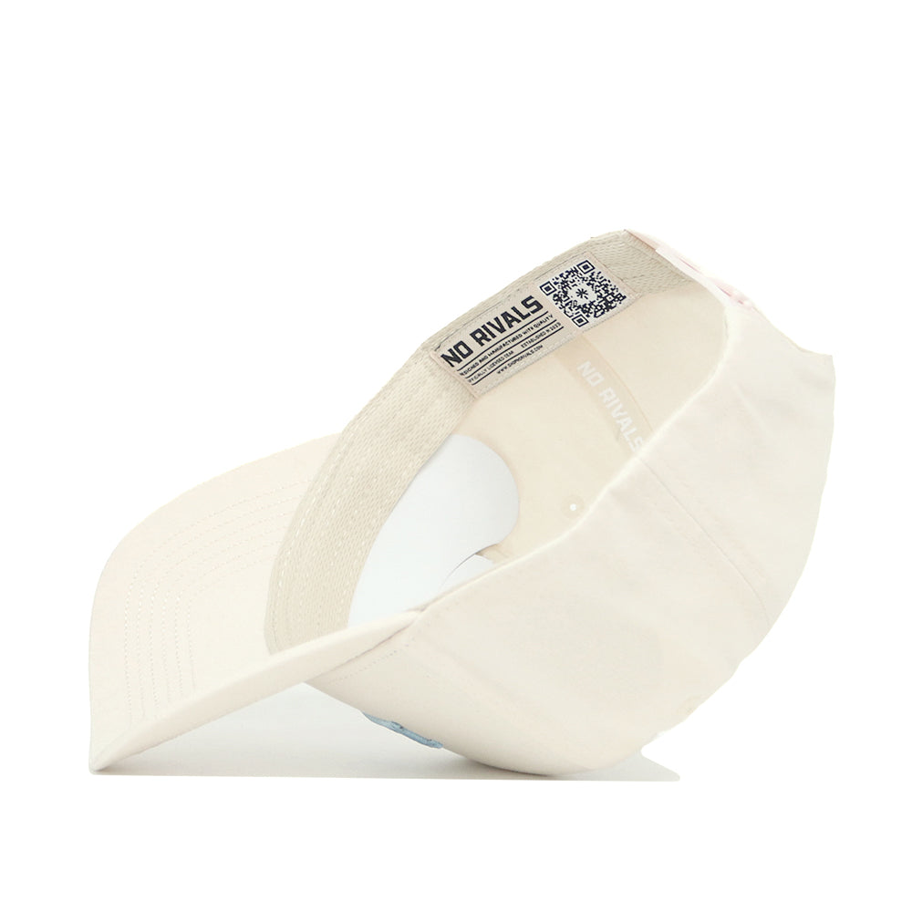 The North Carolina Sideline Hat by No Rivals is a cream-colored, structured baseball cap shown upside down to reveal its interior label and QR code on the inner band. Made from high quality cotton, it features a slightly curved brim.