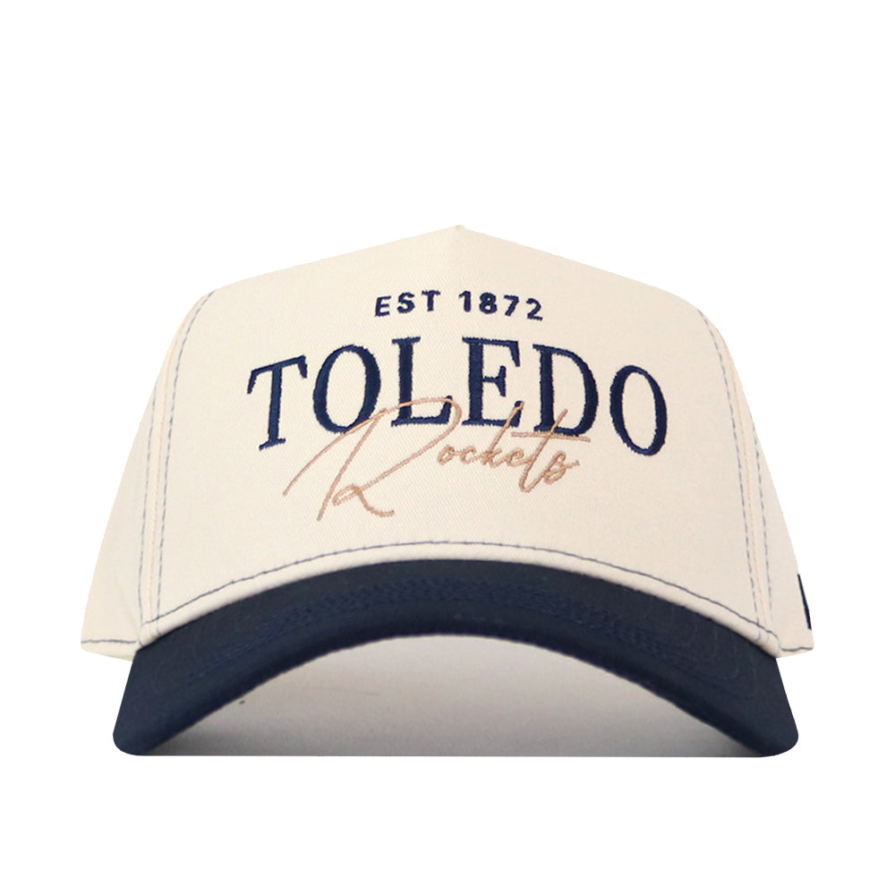 The No Rivals Toledo Rockets Vintage Hat is a white and navy baseball cap featuring EST 1872 TOLEDO Rockets printed on the front in bold blue and gold lettering, an officially licensed embroidered logo, and an adjustable snap back closure for a perfect fit.
