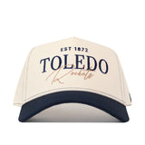 The No Rivals Toledo Rockets Vintage Hat is a white and navy baseball cap featuring EST 1872 TOLEDO Rockets printed on the front in bold blue and gold lettering, an officially licensed embroidered logo, and an adjustable snap back closure for a perfect fit.