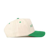 A side view of the No Rivals North Dakota Vintage Hat is displayed against a white background. This cream-colored baseball cap features green stitching, matching eyelets, and a green brim, accented with an officially licensed embroidered logo.