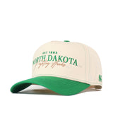 Introducing the North Dakota Vintage Hat by No Rivals, featuring a beige and green design with “North Dakota Fighting Hawks EST 1883” embroidered on the front in striking green and gold lettering. This officially licensed cap comes with a green bill, an embroidered logo, and “ND” detail on the left side. The snap back closure offers a comfortable and adjustable fit.
