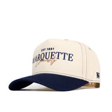 The No Rivals Marquette Vintage Hat is a cream and navy snapback with "EST 1881 Marquette University" embroidered on the front, a structured fit, navy brim, small NF logo on the side, and made from high-quality cotton.