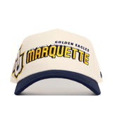 The Marquette Alma Mater Hat by No Rivals is a white snapback with a navy blue brim, made from premium cotton. It features GOLDEN EAGLES MARQUETTE and a logo embroidered on the front, and is officially licensed for fans.