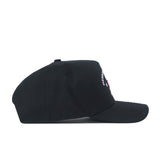 The Nebraska Outlaw Hat - Black by No Rivals is shown from the side, featuring a curved brim and visible stitching. Small embroidered logo text and a red square detail appear on the front panel, though the full text isn’t readable from this angle—perfect for adding a subtle touch to your gameday fit.