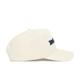 The No Rivals West Virginia Sideline Hat is a cream-colored cotton baseball cap with a curved brim and small navy blue embroidered logo on the front, shown in side profile against a plain white background.