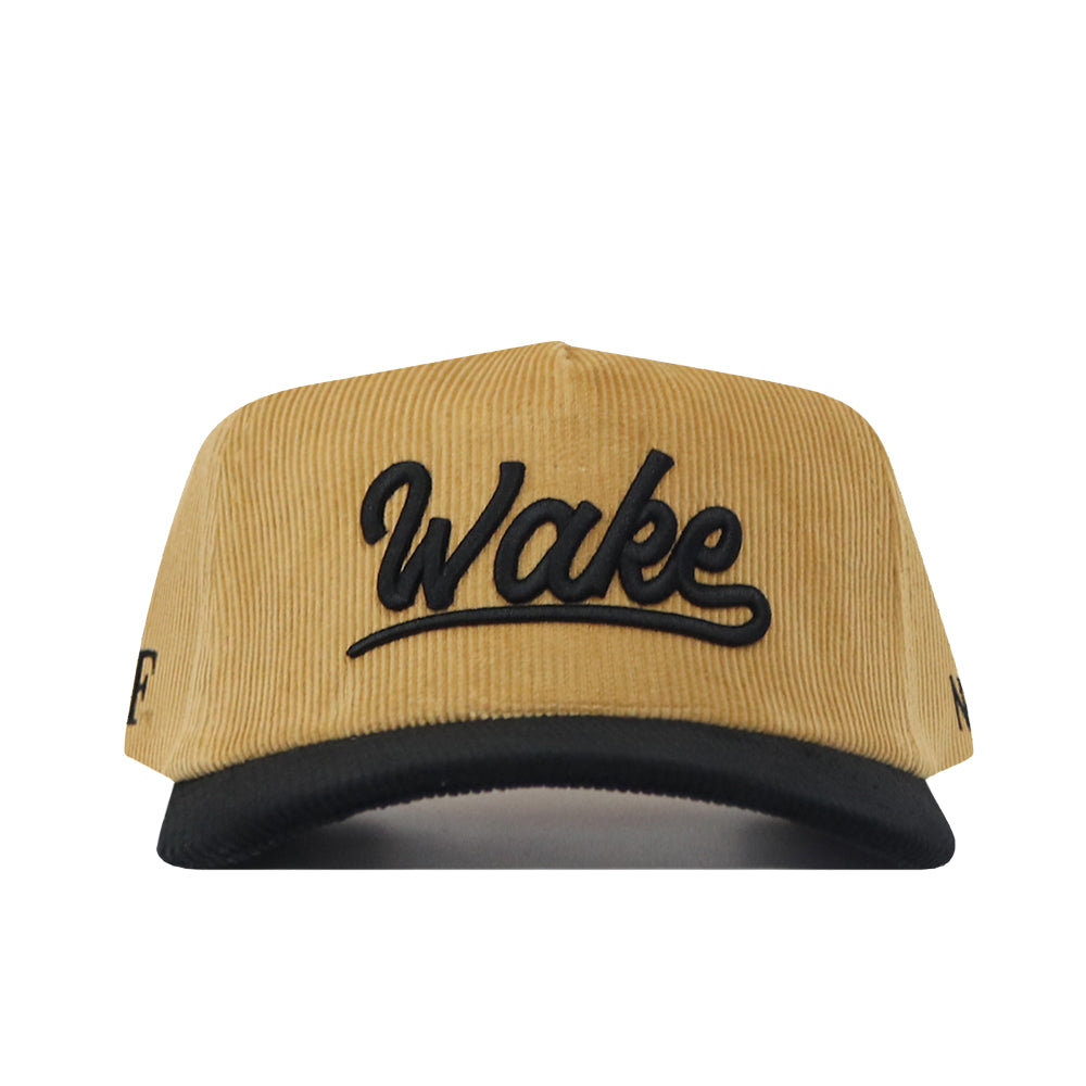 A two-tone Wake Forest Gold Rush hat by No Rivals, made from tan corduroy with an unstructured fit, featuring a black brim and “Wake” embroidered in black cursive on the front.