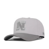 Introducing the Nebraska Graphite Hat by No Rivals—a light gray snapback cap featuring a raised, embroidered silver N logo on the front and a smaller N on the side. Made of fabric with a curved brim, this officially licensed hat combines classic style with team pride.