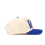 The Kansas Jayhawks Stride Hat by No Rivals is a cream-colored snapback featuring a blue brim and blue 3D embroidered logos on the front, displayed in a left-side profile view against a white background.