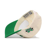 A cream and green Right Side Up Marshall Hat by No Rivals lies on its side, displaying its green brim and the NO RIVALS text inside. This cap offers a structured fit for lasting shape, with an embroidered X logo and THE GODS text on the front.
